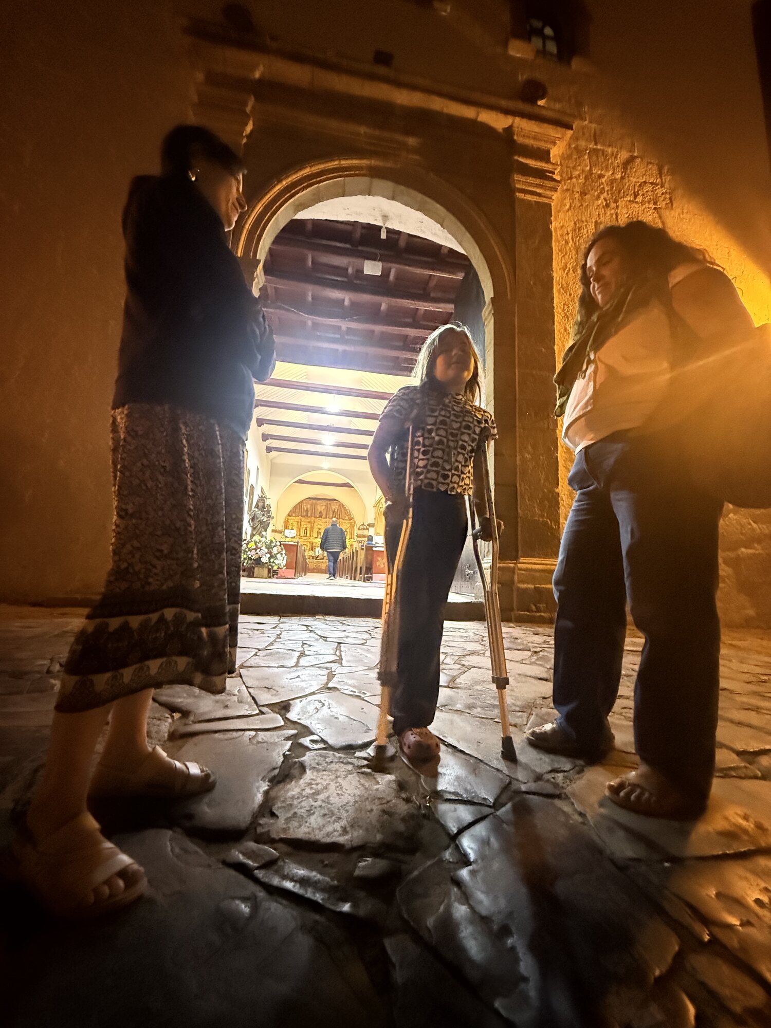 Silhouetted figures in a warm-lit archway, crutches on a stone floor